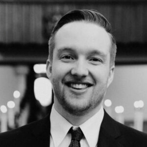 Black and white photo of young man smiling, wearing a suit