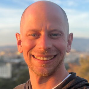 Bald man in front of mountainscape, smiling