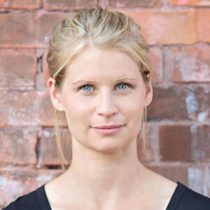 Blonde woman in front of a brick wall.