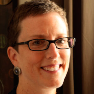 Woman with short brown hair and glasses, smiling